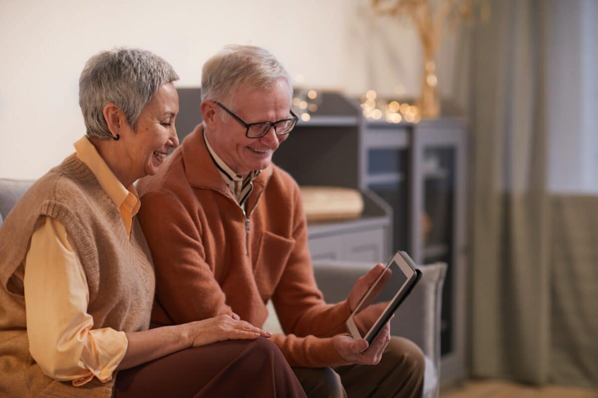 deux personnes d'un certain âge regardent une tablette